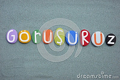 Gorusuruz, turkish word meaning, see you later, composed with multi colored stone letters over green sand Stock Photo