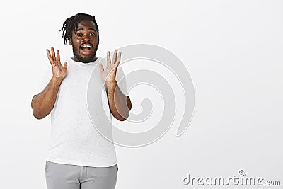 Gosh I am shocked. Portrait of amazed speechless attractive plump guy with dark skin, raising palms and screaming from Stock Photo