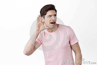 Gossip man trying to overhear someone, hold hand near ear and lean closer to copy space, trying to understand words Stock Photo