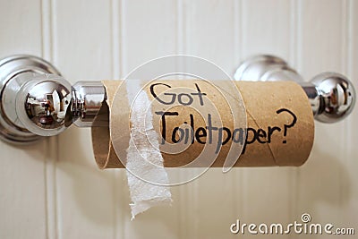 `Got Toilet Paper`, written in sharpie on cardboard toilet paper roll that is left hanging on the spool, on the wall Stock Photo