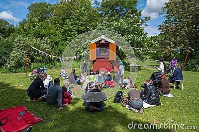 Kids and parents watching a puppetry show in a park.. Editorial Stock Photo