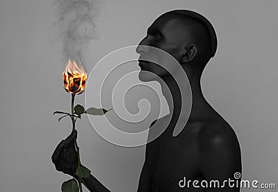 Gothic and Halloween theme: a man with black skin holding a red rose, black death isolated on a gray background in studio Stock Photo