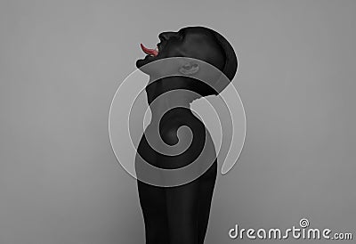 Gothic and Halloween theme: a man with black skin holding a red rose, black death isolated on a gray background in studio Stock Photo