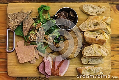 Gourmet platter with duck pate, foie gras, duck confit and seared duck breast on a wooden cutting board in a restaurant Stock Photo