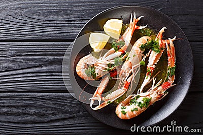 Gourmet seafood scampi or langoustine or Norway lobster are served on a black plate with sauce and lemon. horizontal top view Stock Photo