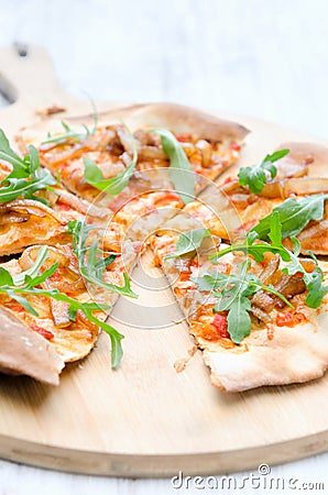 Gourmet thin crust pizza with fresh rocket and caramelised onion Stock Photo