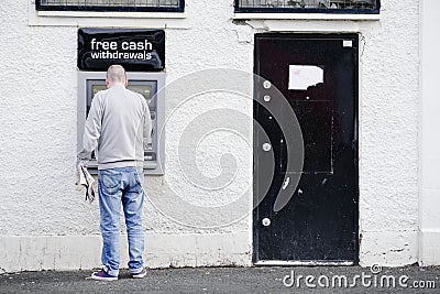 Male person at cash point machine ATM automated free money withdrawal in wall Editorial Stock Photo