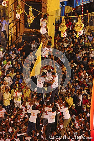 Govindas, young boys surrounded by crowd, making a human pyramid to break Dahi Handi Editorial Stock Photo