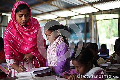 Community teacher in the class busy checking the notebook, math homework by students Editorial Stock Photo