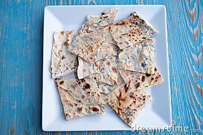 Gozleme,traditional,Turkish baked bread,dish in Turkey.Tasty food, cut tasty flat cake on plate on blue wooden table.Top Stock Photo