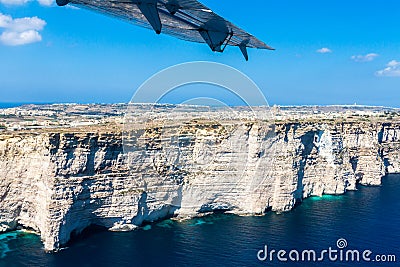 Gozo island from above, under the wing of a small plane. Aerial view of Gozo, Malta. The dome of Rotunda of Xewkija. Stock Photo