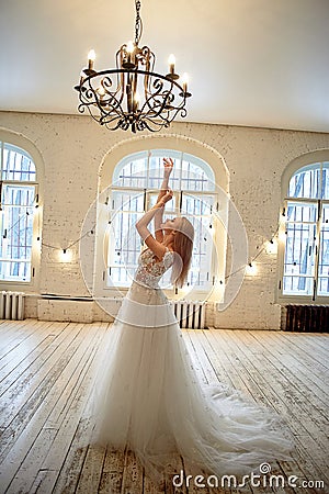 A graceful bride in a lace dress pulls her hands up.Room in loft style. Stock Photo