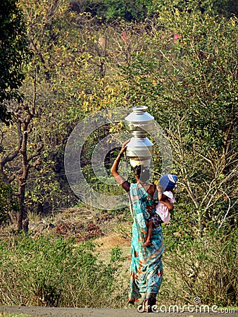 Graceful and strong woman carrying her baby and water containers on her head in Purushwadi. Editorial Stock Photo