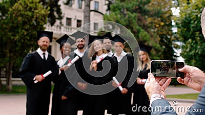 Graduation day for a group of multiracial graduates students posing with a large smile very excited in front of the Stock Photo