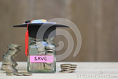 Graduation hat on glass bottle with Stack of coins money on wood Stock Photo