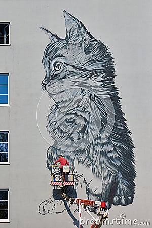 Graffiti artist on aerial work platform drawing cat graffiti on house wall, urban space decoration Editorial Stock Photo