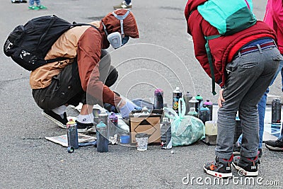 Graffiti artist painting. Street artist painting colorful graffiti asphalt. Urban man performing. Concept of modern art. Small boy Editorial Stock Photo