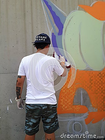 Graffiti artist spray paints a piece on a wall Editorial Stock Photo