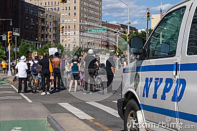 Grand army Plaza. Protesters walking holding signs followed by a NYPD van Editorial Stock Photo
