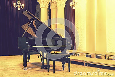 Grand Piano in Concert Hall. Piano standing on empty stage. opened black grand piano with stool on a wooden concert Stock Photo