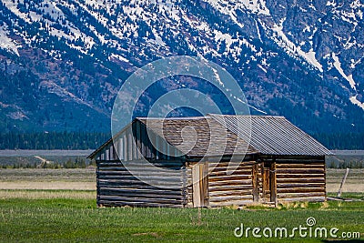 Grand Teton National Park, Wyoming. Wood Cabin on a Golden Grass Prairie against the Grand Teton Mountains. Stock Photo