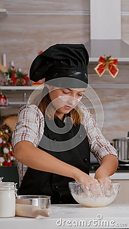 Grandchild wearing apron preparing homemade winter biscuits dough in culinary kitchen Stock Photo