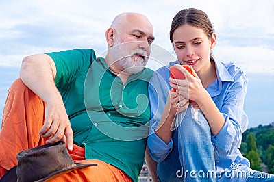 Granddaughter with elderly grandfather. Senior man Granddad with mobile phone smiling make self portrait webcam view Stock Photo