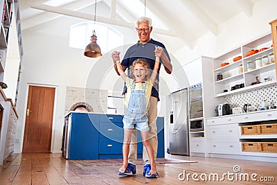 Granddaughter Playing Game Walking On Grandfathers Feet At Home Stock Photo