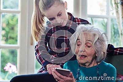 Teenage Granddaughter Showing Grandmother How To Use Mobile Phone Stock Photo