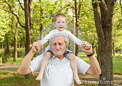 Grandfather carrying grandson on shoulders. Senior man and grandson Stock Photo