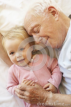 Grandfather Cuddling Granddaughter In Bed Stock Photo