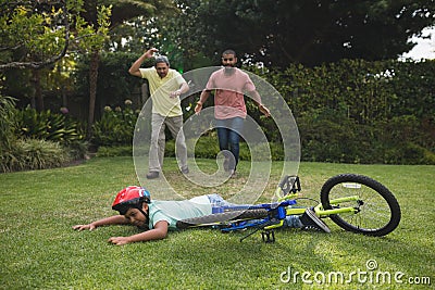 Grandfather and father running towards fallen boy with bicycle Stock Photo