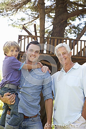 Grandfather, Father And Son Standing By Tree House Together Stock Photo