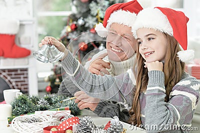 Grandfather with granddaughter in Santa hats preparing for Christmas at home Stock Photo