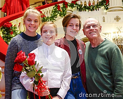 Grandfather and 3 granddaughters standing on stairway decorated for Christmas Stock Photo