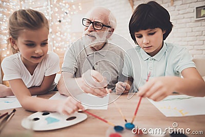 Grandfather, grandson and granddaughter at home. Children are painting. Stock Photo