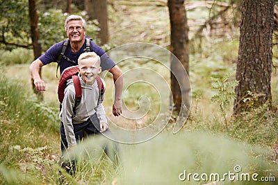 Grandfather and grandson hiking in a forest amongst greenery, front view Stock Photo