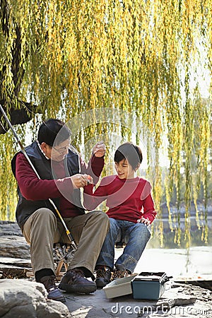 Grandfather and grandson putting lure on fishing line Stock Photo
