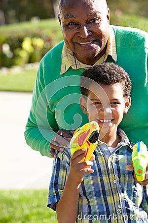 Grandfather And Grandson Shooting Water Pistols Stock Photo