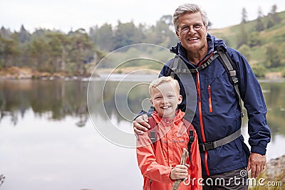 Grandfather and grandson standing together on the shore of a lake smiling to camera, close up, Lake District, UK Stock Photo