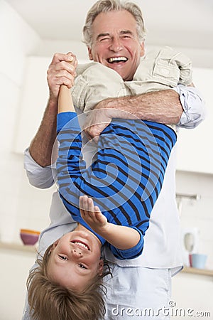 Grandfather Holding Grandson Upside Down At Home Stock Photo