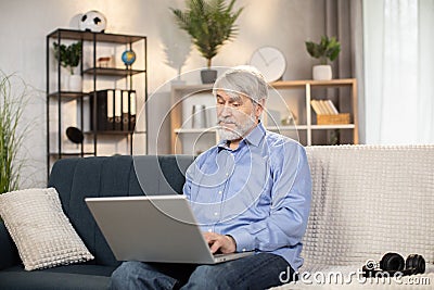 Grandfather looking through kids' photos on computer indoors Stock Photo