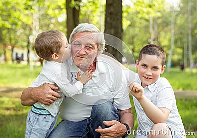 Grandfather playing with grandchildren. Boys hugging his grandfather Stock Photo