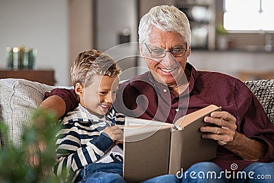 Grandfather reading fairy tales book to cute boy Stock Photo