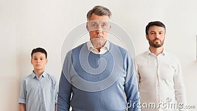 Grandfather Standing Between Son And Grandson Against White Wall, Panorama Stock Photo