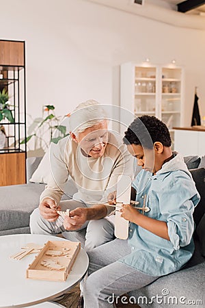 Grandfather telling something to his multiracial son while he is playing Stock Photo