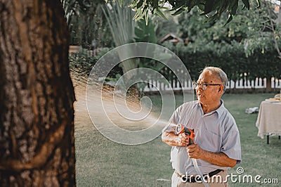 Grandfather water the plants in garden alone. Retirement age lifestyle on backyard Stock Photo