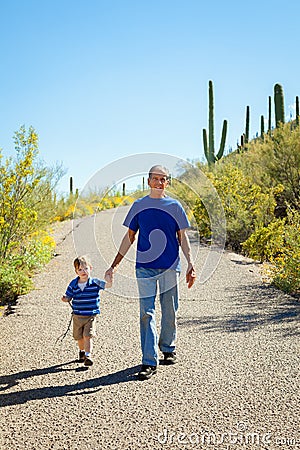 Grandfather and Young Grandson Hike Downhill, Holding Hands on a Stock Photo