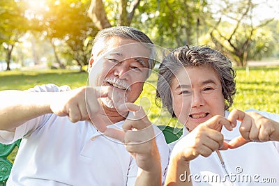 Grandma and grandpa or grandparents make symbol of love by using hands and fingers for making hearts. Lovely older couple or Stock Photo