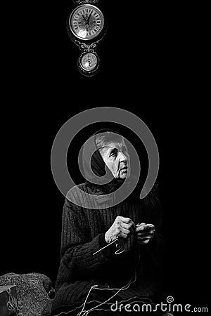 Grandma knitting. Black-and-white low key photograph on black background. Stock Photo